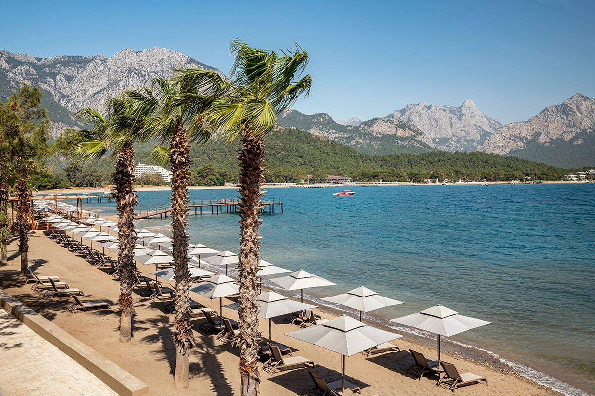 Strand des NG Phaselis Bay mit Liegen, Meer und Taurusgebirge