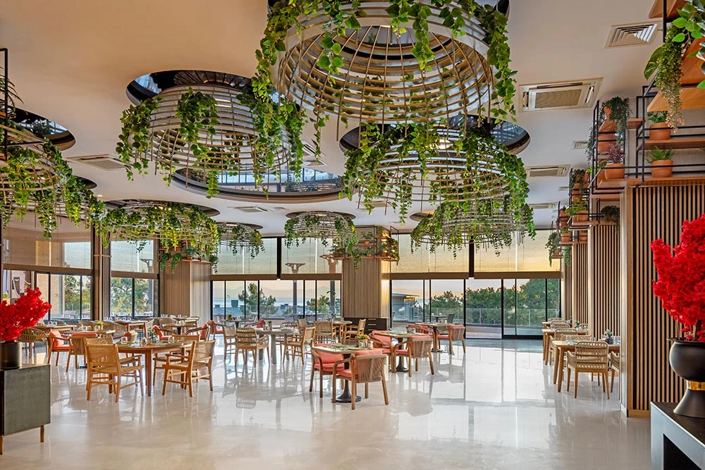 Heller Restaurantbereich des NG Phaselis Bay mit Pflanzen und Meerblick