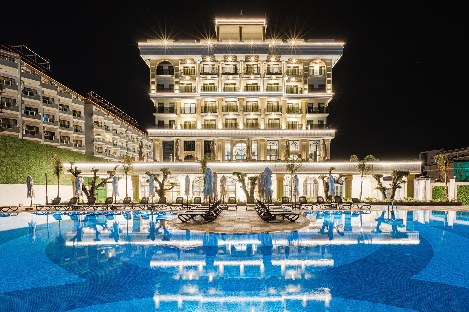 Serenity Queen Hotel mit beleuchtetem Hauptgebäude und Pool bei Nacht